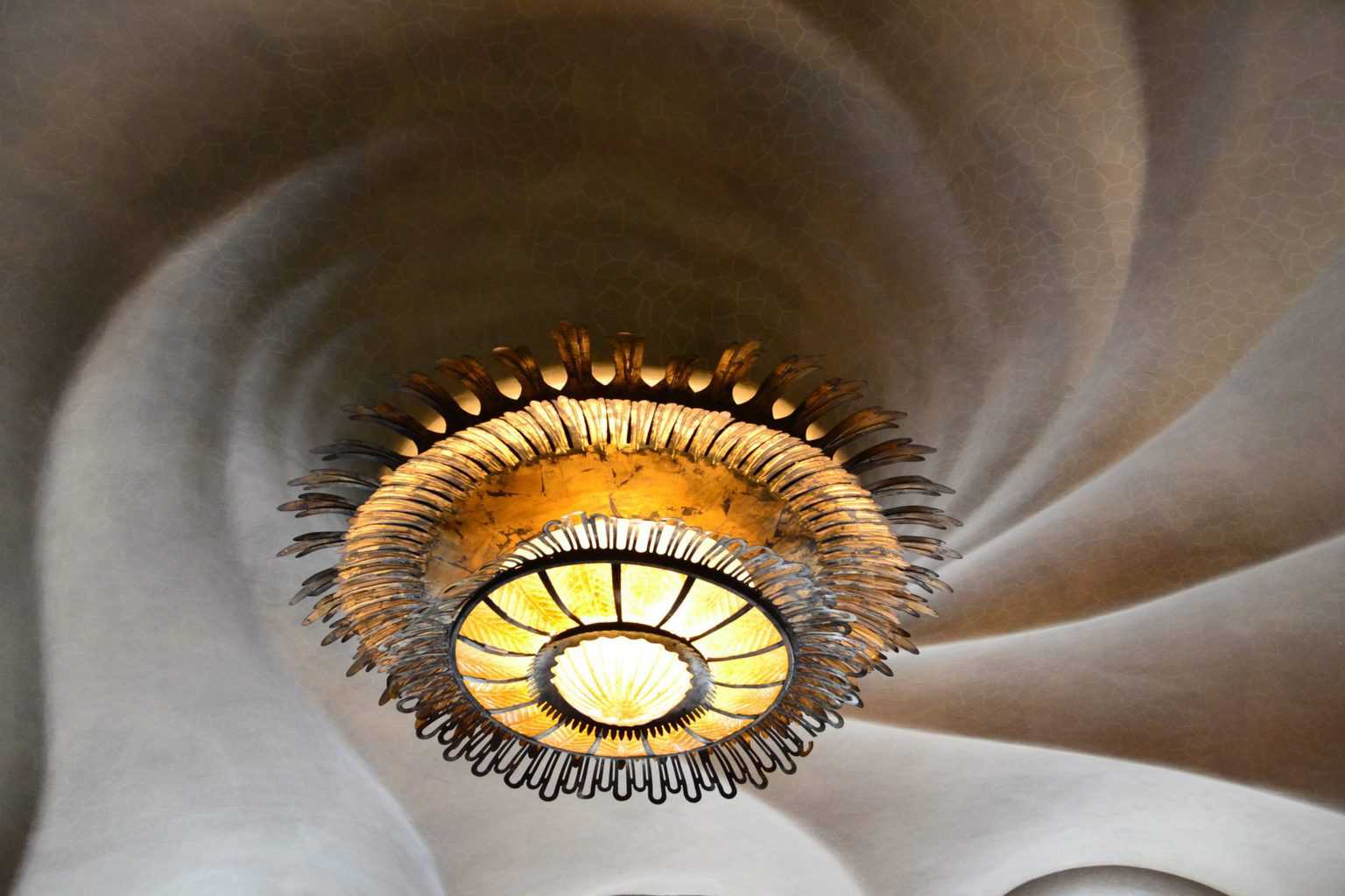 A circular lamp on the ceiling of Casa Batllo. This is a must-see when traveling solo in Barcelona.
