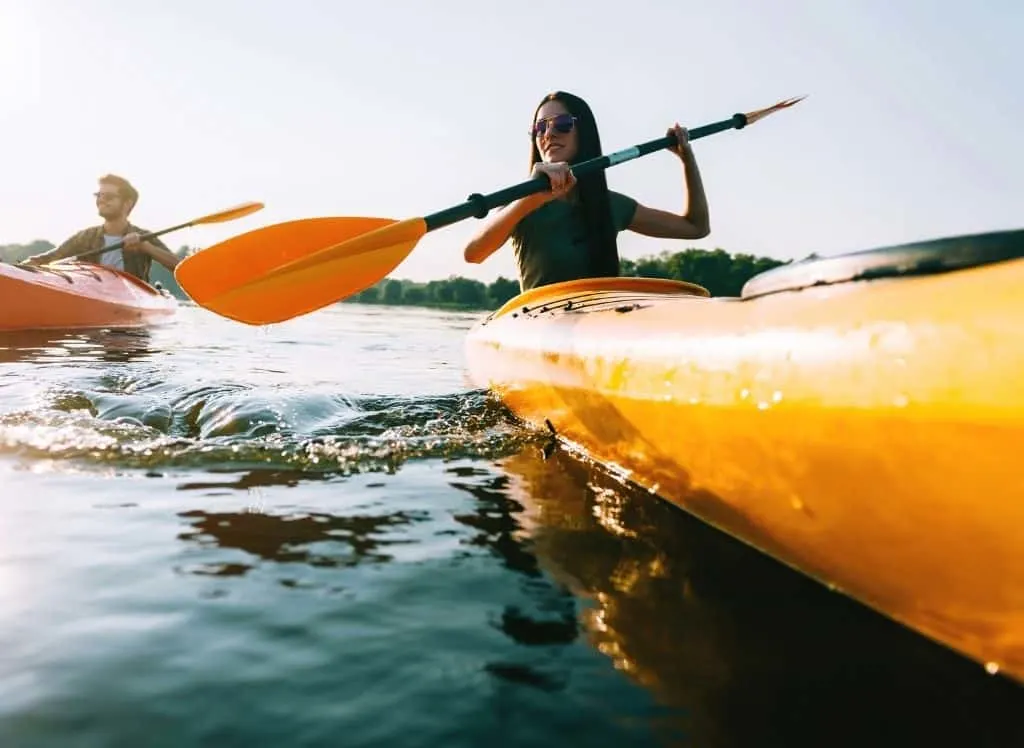 A man and woman going kayaking through the water. 