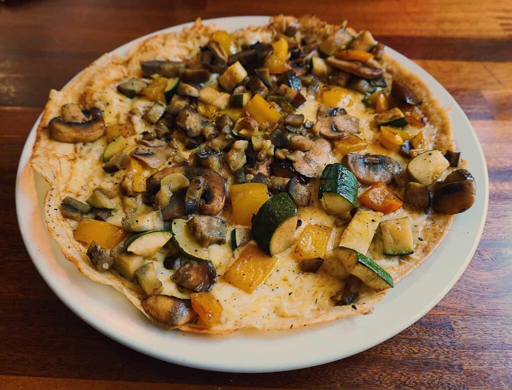 View of a classic Dutch pancake with mushrooms and squash on top. You can try it during one of the best food tours in Amsterdam. 