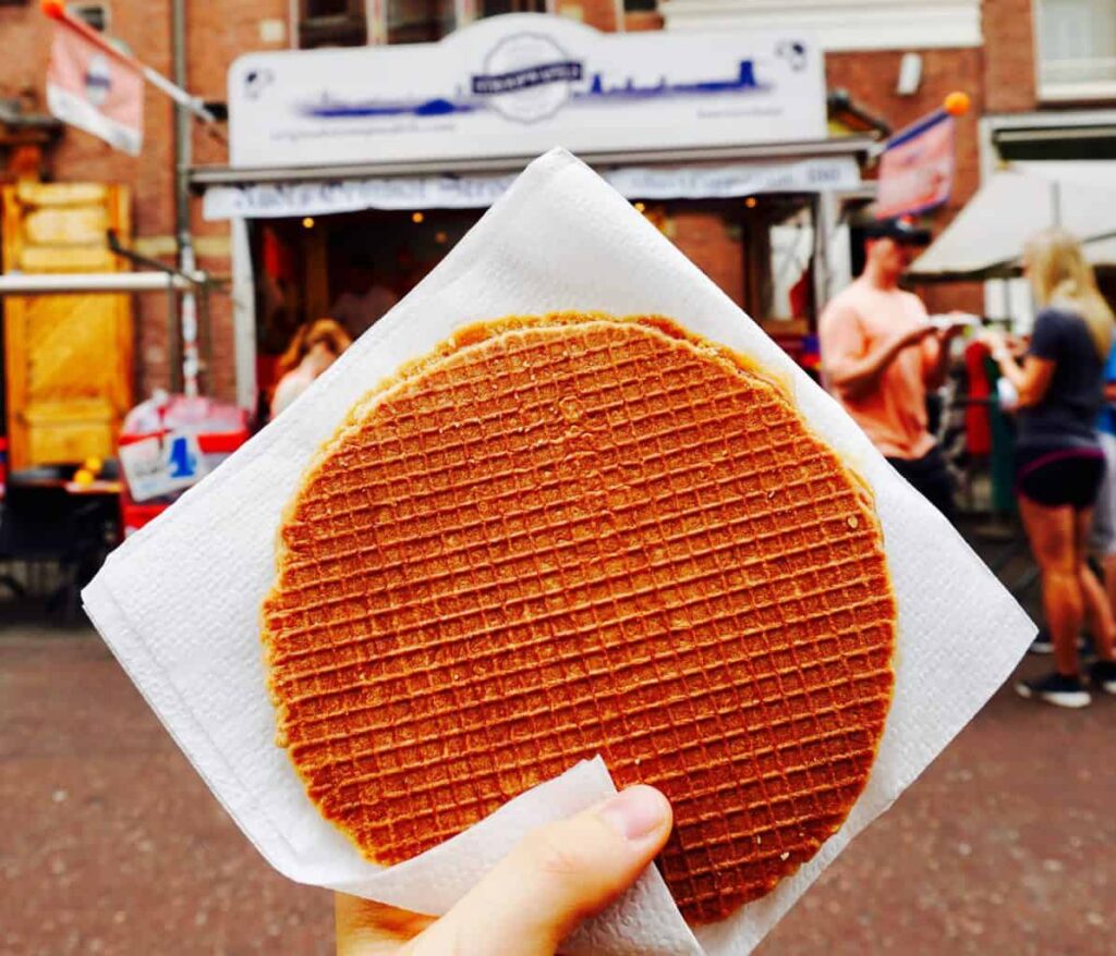 Me holding a Stroopwafel from Albert Cuyp Market during my 3 days in Amsterdam itinerary,.