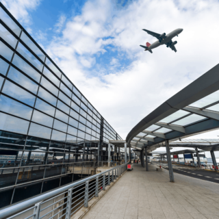 View of a modern airport with a plane flying through the sky.