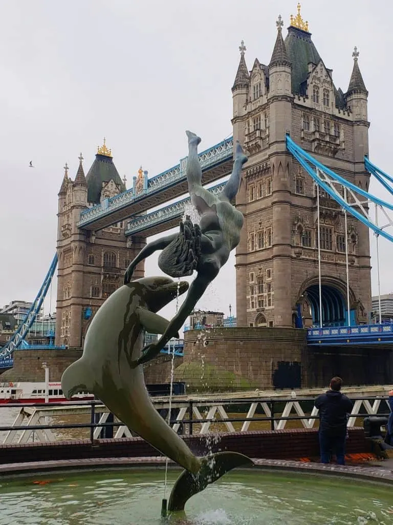 An iconic view of the Girl with a Dolphin fountain, with Tower Bridge in the background, from Saint Katherine's Pier.