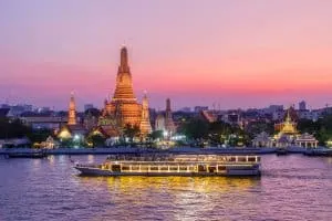The beautiful Wat Arun lit up in the evening by the Chao Phraya river in Bangkok.