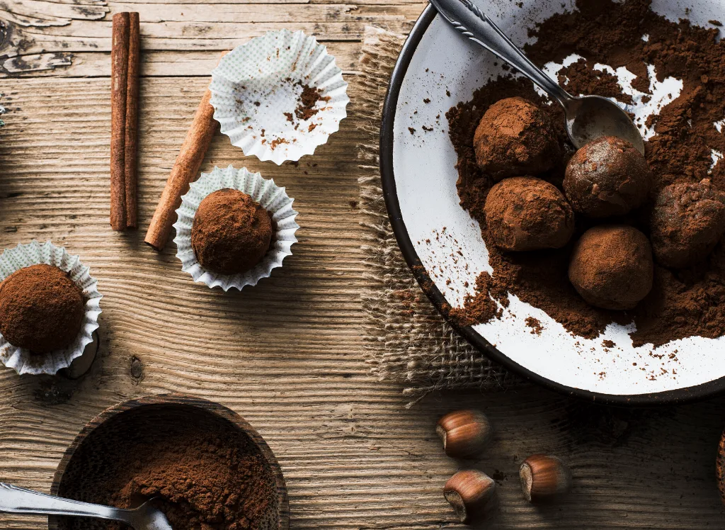 Chocolate truffles in a bowl on a wooden table. 