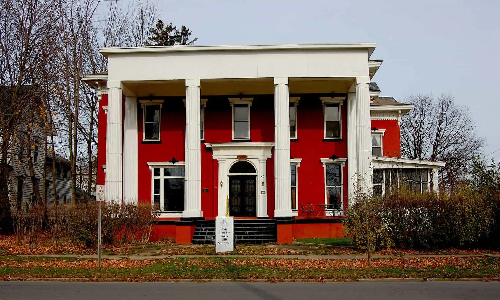 The beautiful, red exterior of the Erie Mansion Bed and Breakfast with giant white columns. One of the most haunted hotels in New York. 