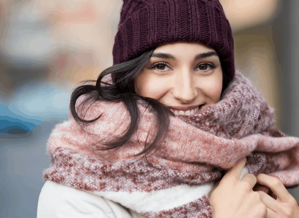 Woman wearing a warm scarf and hat - all of which are essential when packing for colder climates.