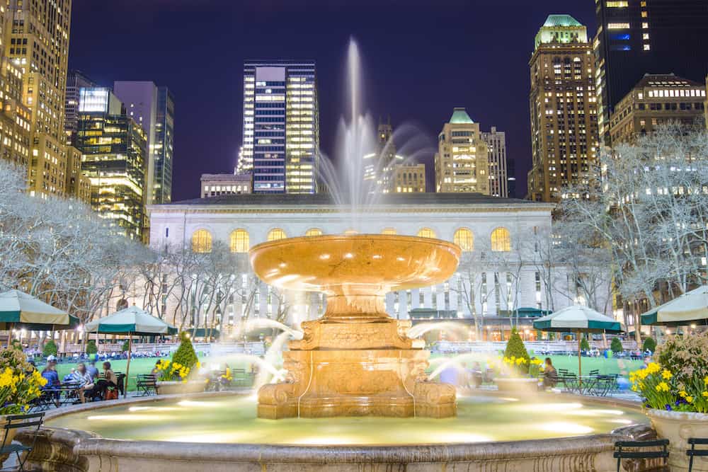 View of the fountain in Bryant Park with the New York Public Library in the background.