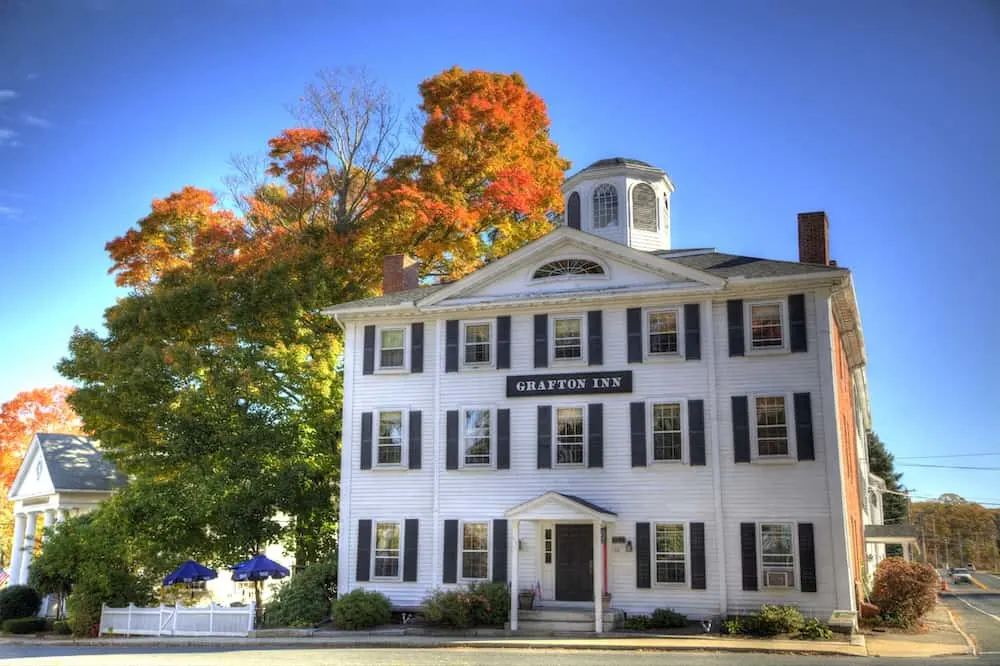 The white facade of the Grafton Inn with vibrant fall foliage in the background. 