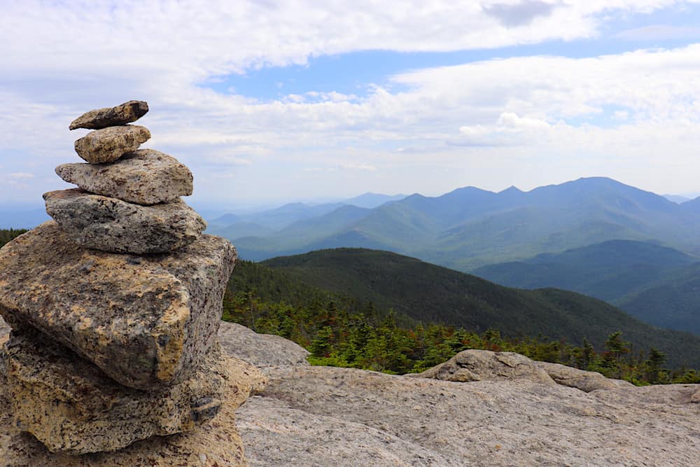 The rocks stacked together in front of the panoramic view from the top of Rocky Peak Ridge which is another fun but hard hike in the Adirondacks.