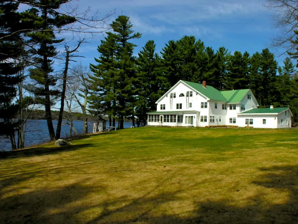 The white exterior and green roof of the Wolf Cove Inn in Poland, Maine