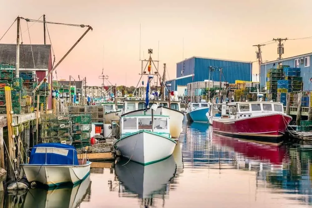 The colorful fishing boats docked at the harbor in Portland, Maine with the setting sun in the background is just one of the stops on this road trip in Maine.