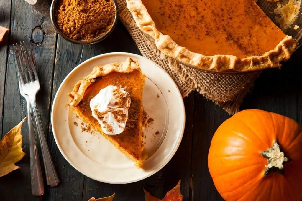 A slice of pumpkin pie with whipped cream on top. 