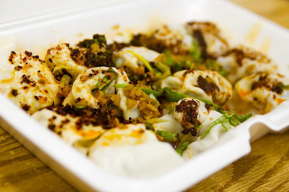 An order of spicy dumplings in a styrofoam container from White Baar in Flushing, Queens.