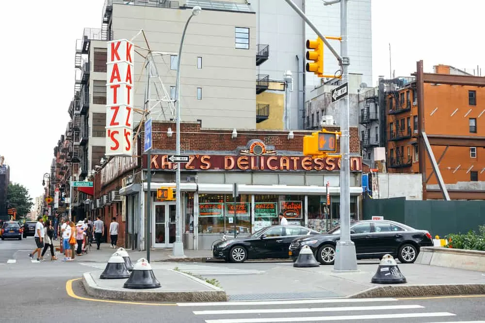 The exterior of Katz's deli on the Lower East Side of NYC with people walking out front.