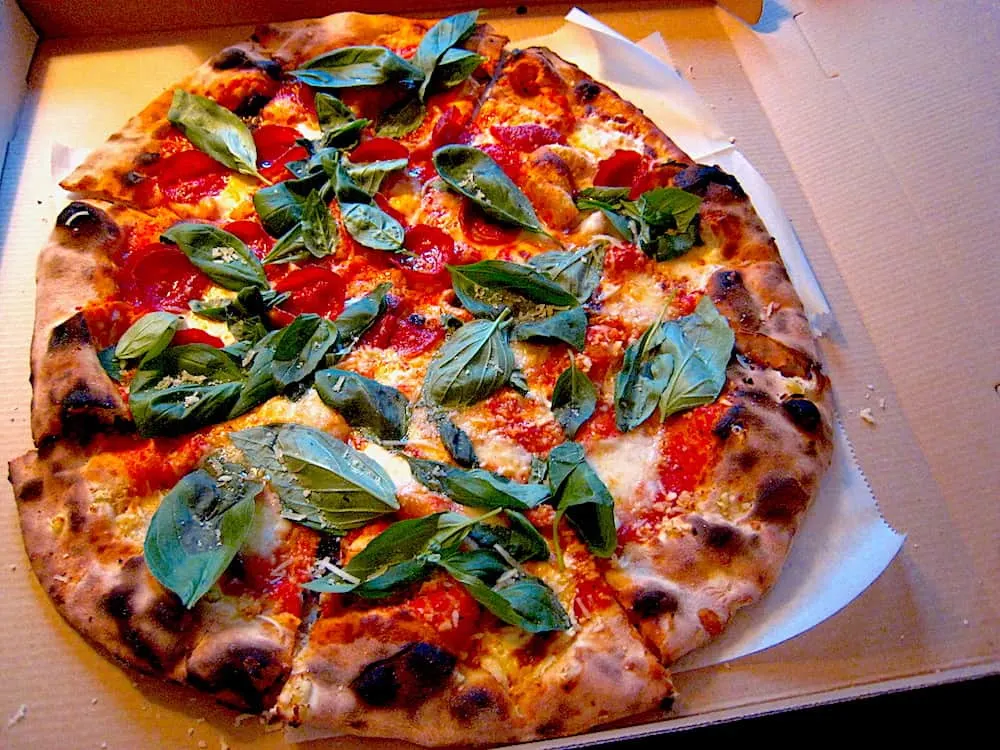 A Margarita pizza with fresh basil on top in a box from Lucali in Brooklyn.