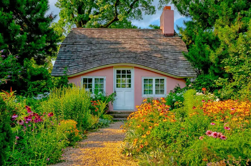 The pink playhouse surrounded by flowers at Planting Fields Arboretum. 