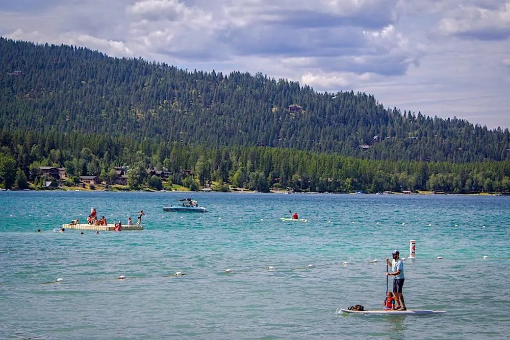 People swimming, kayaking, and paddle boarding in Whitefish Lake in Montana. 