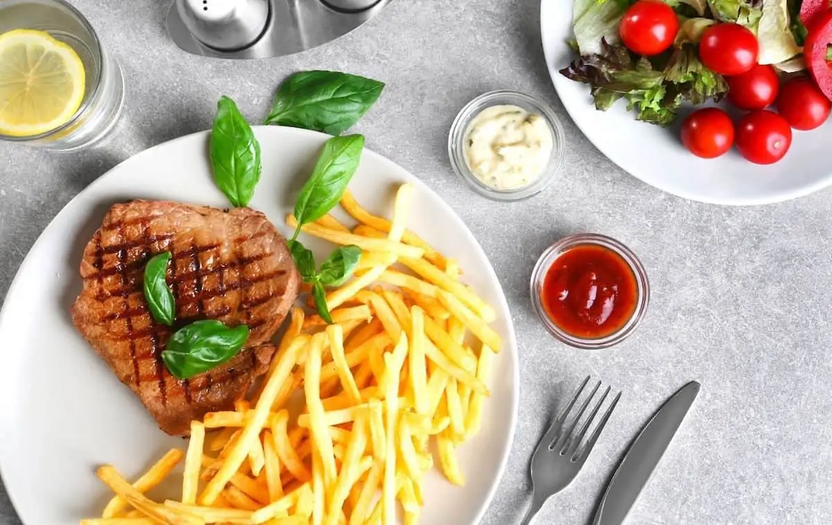  steak and fries on a white plate on a table