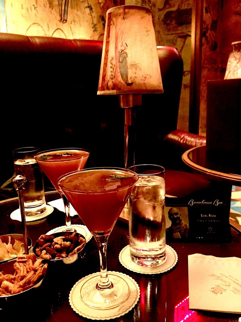 Classic cocktails on a dimly lit table in the Bemelmans Bar in the Carlyle Hotel.. One of the best things to do this Christmas in New York City. 
