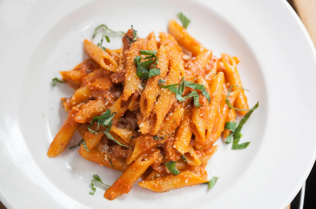 Penne pasta on a white plate from Ainslie in Brooklyn, a top bottomless brunch in NYC. 