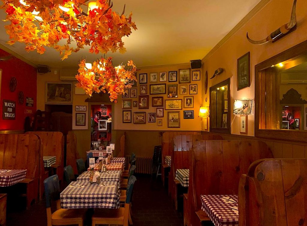 The western-style dining room of Cowgirl NYC with checked table cloths and wooden seats. It is one of the best-themed restaurants in NYC. 
