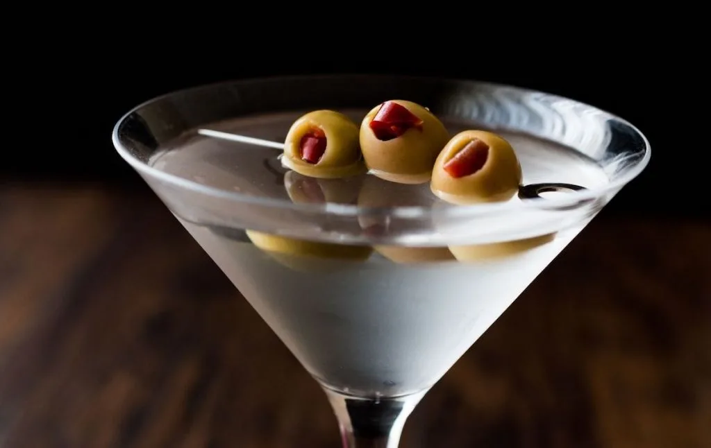 Classic martini with olives in a clear martini glass served up at Beauty bar  which is one of the cooled themed restaurants in NYC.