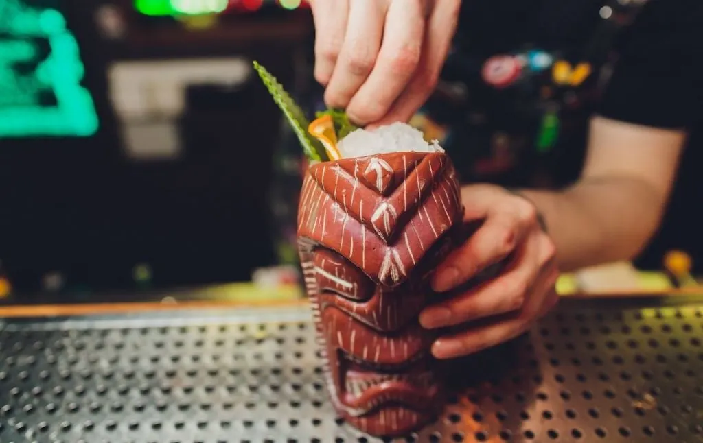 Bartender making a drink in a Tiki-themed glass at one of the best them bars in NYC. 