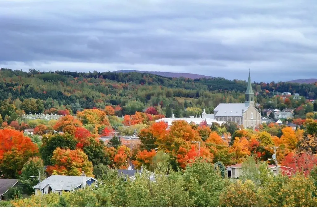 Fall foliage and church steeple in small villages in eastern townships during your Quebec road trip itinerary. 