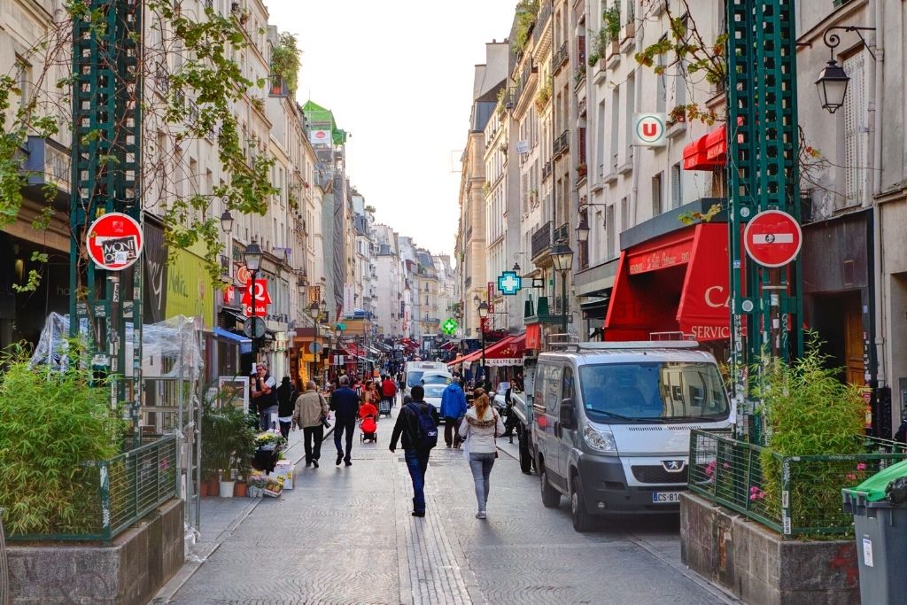 Pedestrians walking down Rue Montorgueil, one of the best streets in Paris known for food. 
