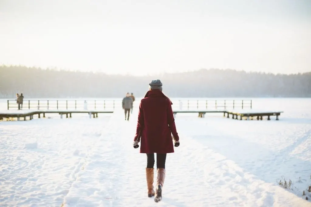 Women walking through the snow in her winter jacket. 