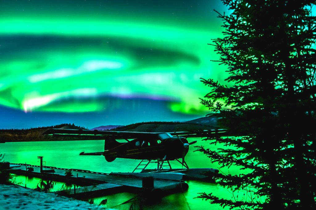Seaplane in the Yukon with the northern lights in the background during the best time to visit Canada. 