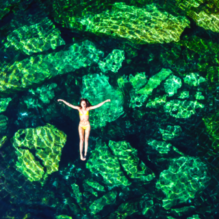 A woman in a bikini floating through the water at Cenote Cristalino.
