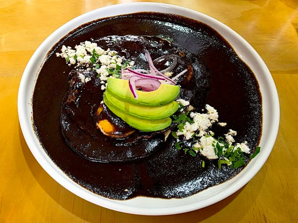 Aerial view of eggs covered in mole sauce and avocado and cheese at Espacio Luvina. 