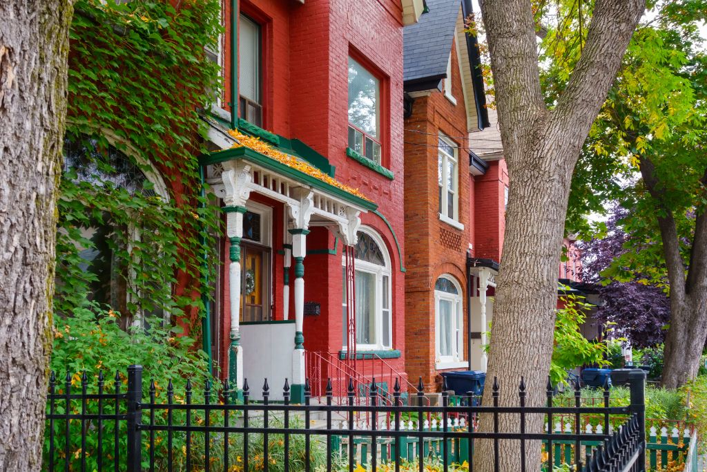 Row of colorful Victorian houses and their gardens in Kensington Market. Visiting them is one of the unique things to do in Toronto.