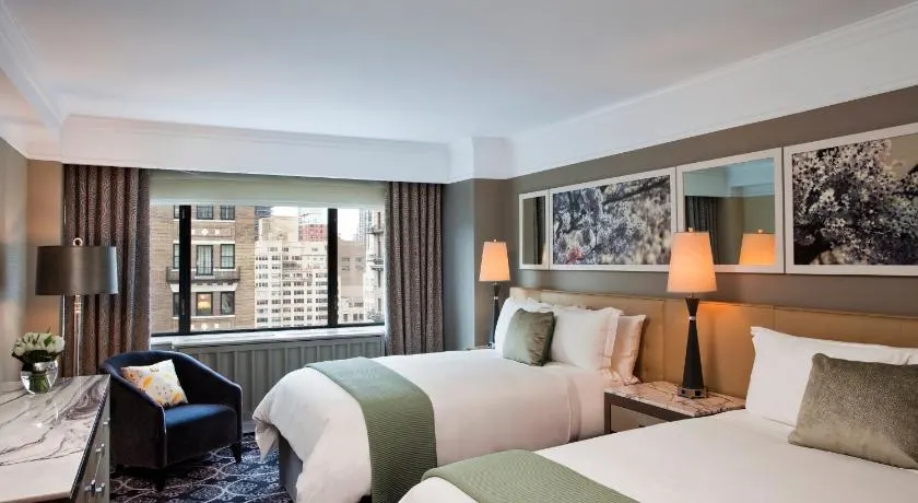 Well-appointed rooms with two twin beds and green pillows inside the Loews Regency. 