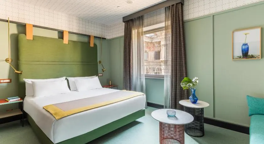 Sleek room with green walls inside Room Mate Giulia. 