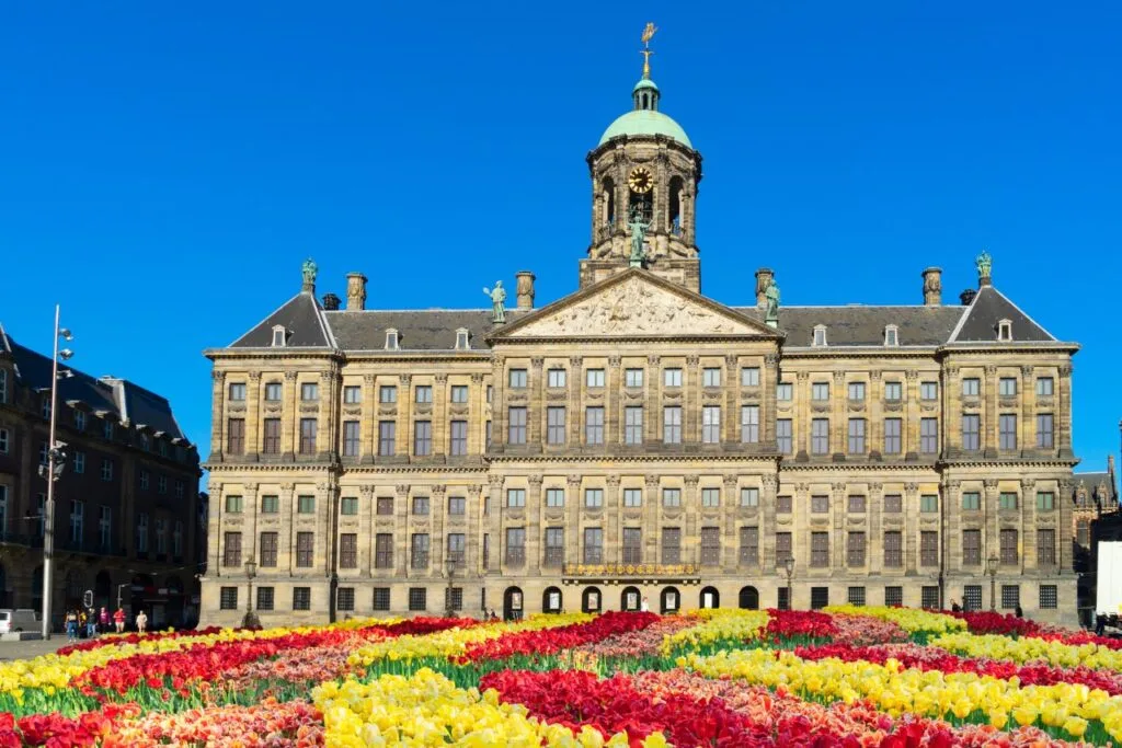 View of the Royal Palace with vibrant tulips out front in Dam Square.