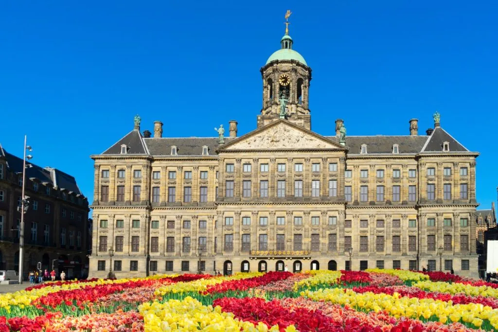 View of the stunning Amsterdam Royal Palace with colorful Tulips out front.