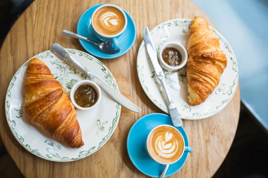 Aerial view of two croissants on plates with lattes in cups on blue saucers at one of the most beautiful cafes in London. 