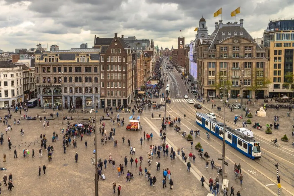 Aerial view of people and trams moving through Dam Square in Amsterdam. 