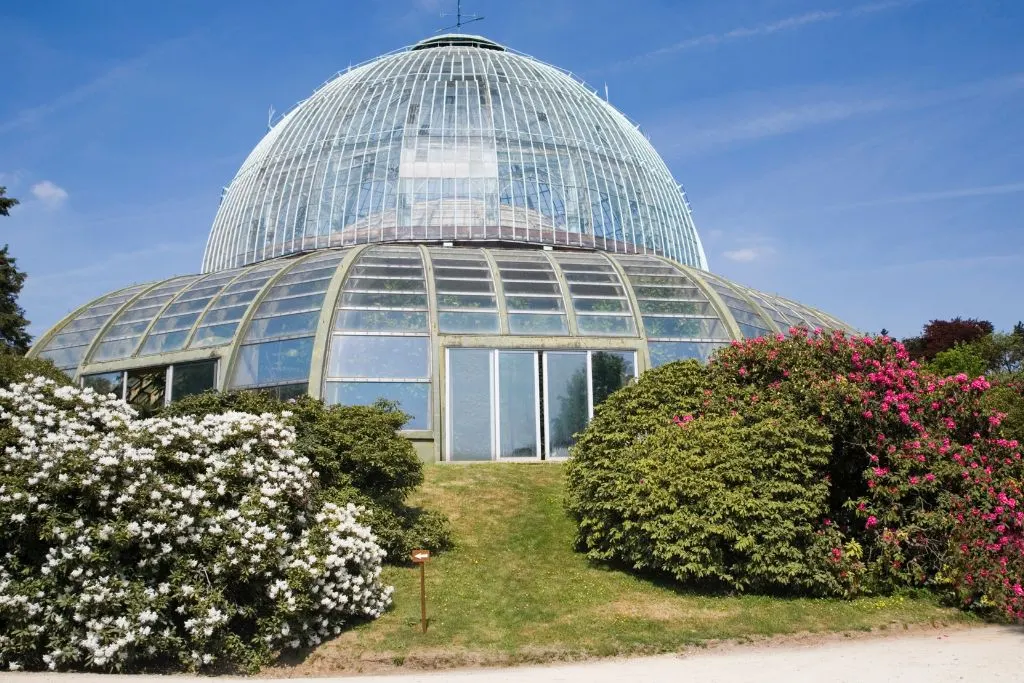 View of the historic and clear Royal Greenhouses of Laeken surrounded by flowers and busges. 