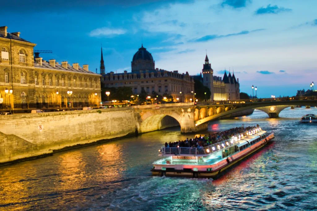 A tourist boat cruising along the Seine in the evening during one of the best champagne tours in Paris. 