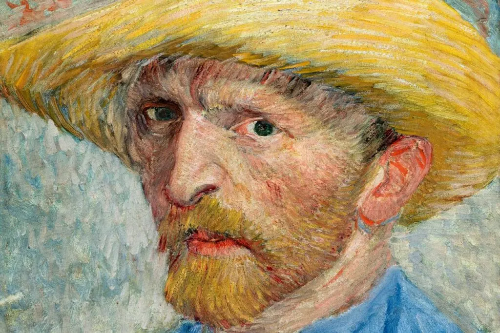 A self-portrait of Vincent Van Gogh in the Van Gogh Museum. He is wearing a blue short and wide brim, tan hat. 