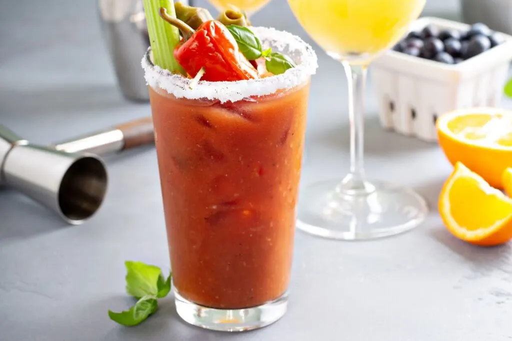 View of a bloody mary with celery and peppers on top at brunch. 