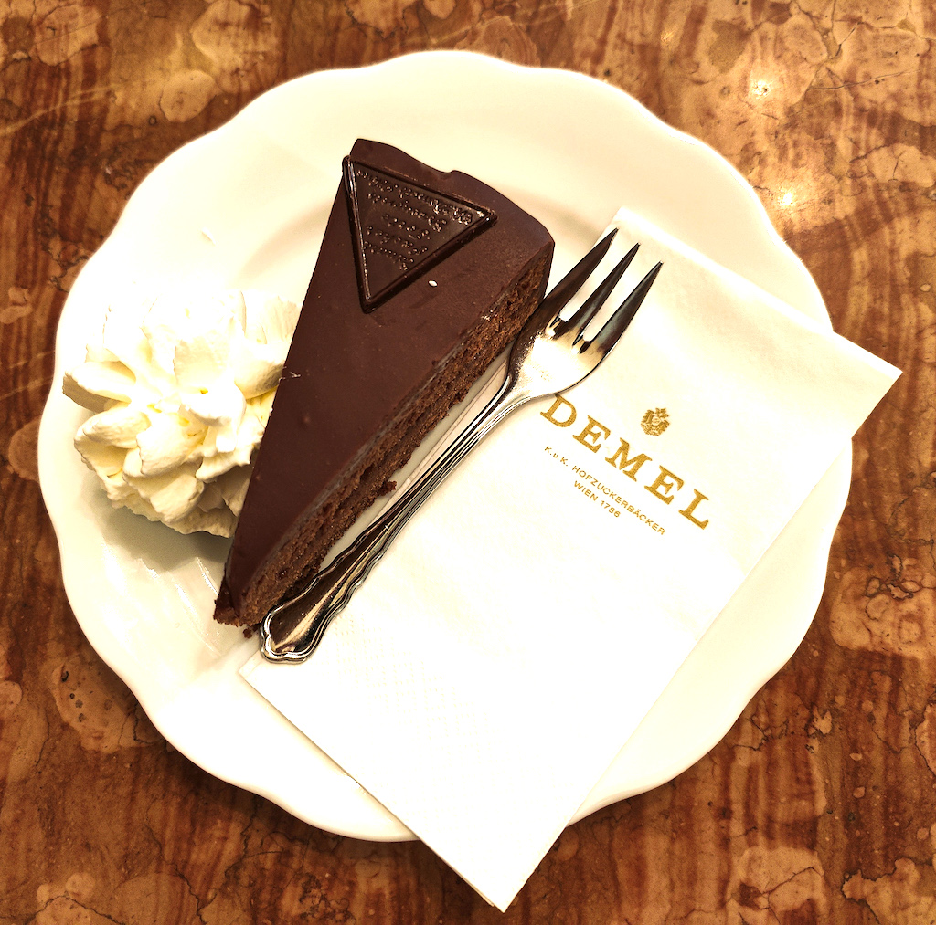 Piece of sachertorte with whipped cream on the side from Cafe Demel. 