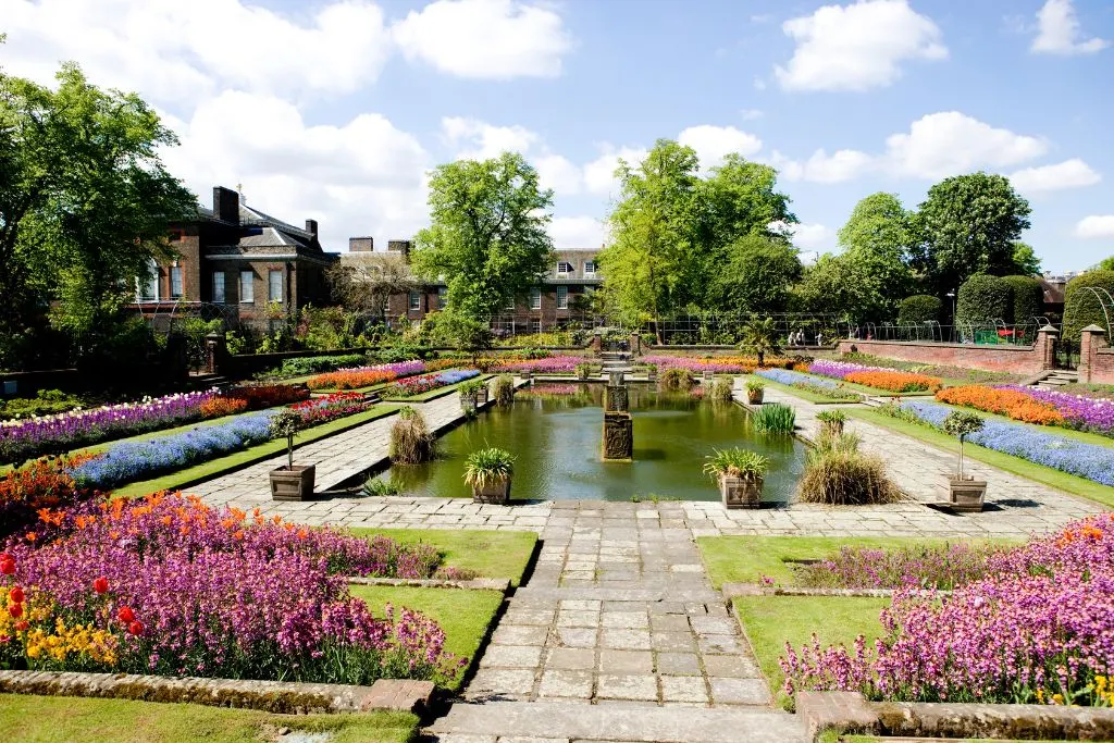 View of the main fountain and well-maintained, vibrant flower beds of Kensington Palace Gardens. 