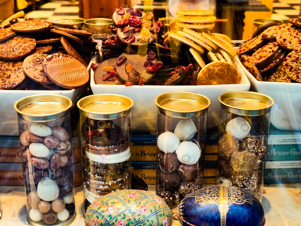 View of chocolates in round tubes with cookies in the back of them at one of the best chocolate stores in Brussels.