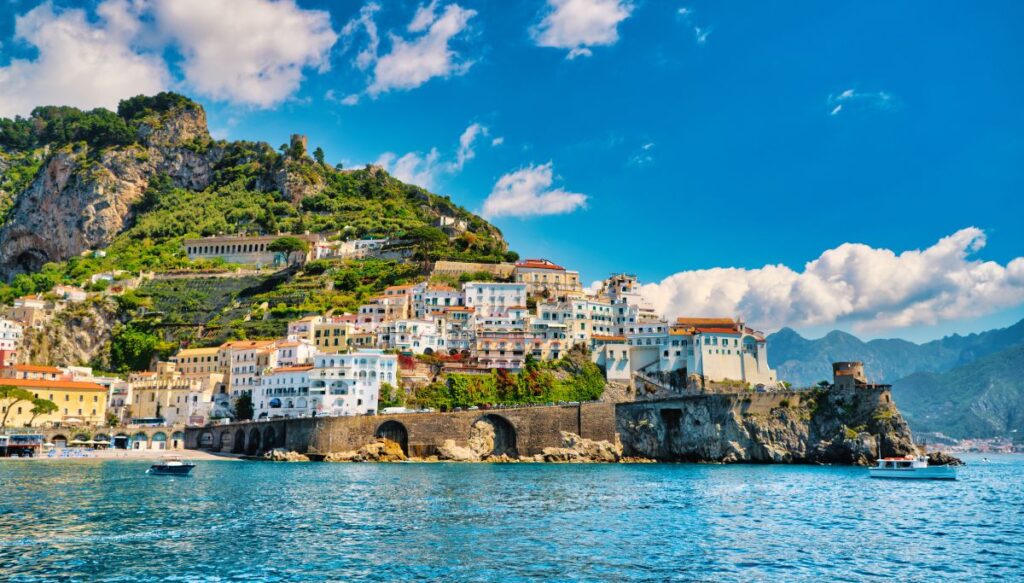 View of the stunning buildings along the coast near Amafli with turquoise blue waters during one of the best tours to Amalfi Coast from Naples.