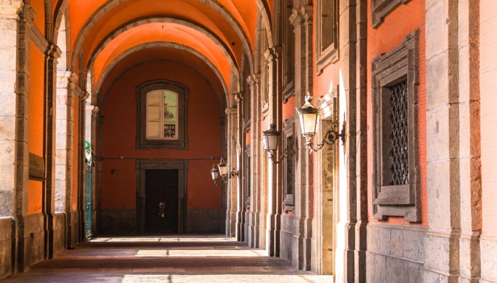 The orange colored hallways of the Royal Palace of Naples have arches ceilings and and are lined with old world lanterns. Be sure to visit if you have one day in Naples. 