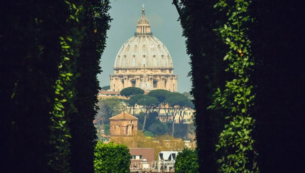 The keyhole view of St. Peter's Basilica from Palentine Hill. The church can be seen through several green bushes.